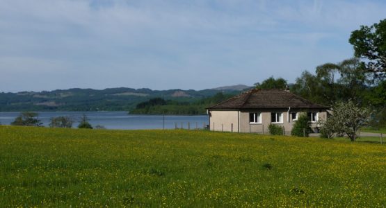 looking onto Loch Awe cottage in a field looking onto a scottish loch