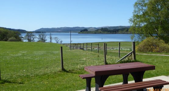 Wonderful views from Barr-beithe Lower garden table looking onto a fence and a loch