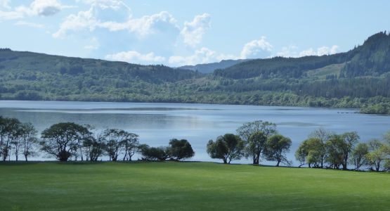 Loch Awe from stable sun shining on Loch Awe with trees and a field